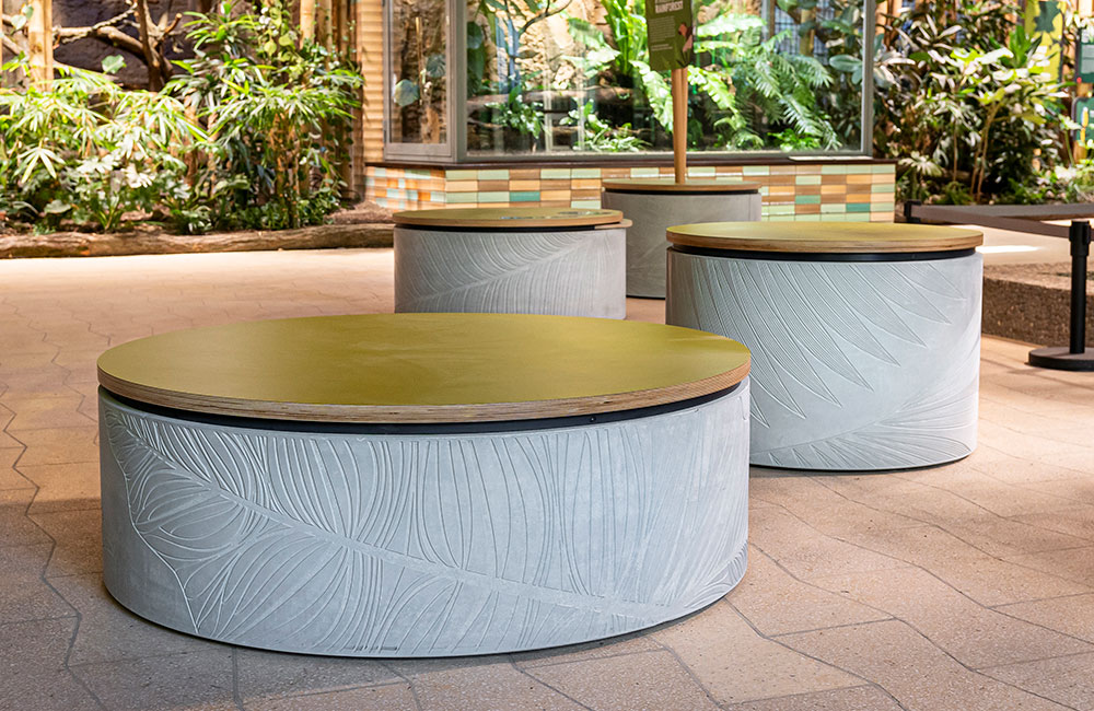 Vier runde Sitzelemente aus Glasfaserbeton vor einem Terrarium